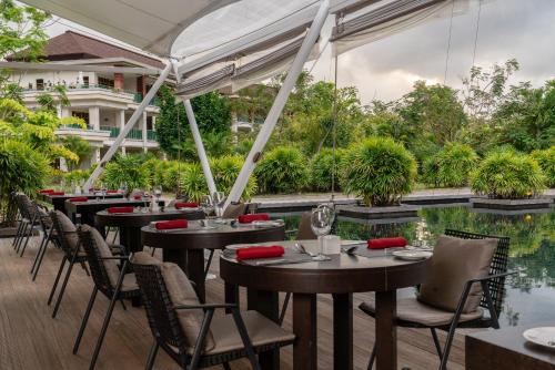 a restaurant with tables and chairs next to a pool at Savoy Seychelles Resort & Spa in Beau Vallon