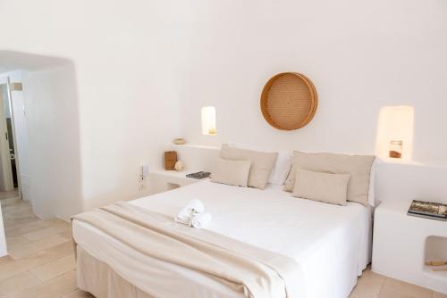 a white bedroom with a white bed with a teddy bear on it at Relais Masseria Villa Cenci in Cisternino