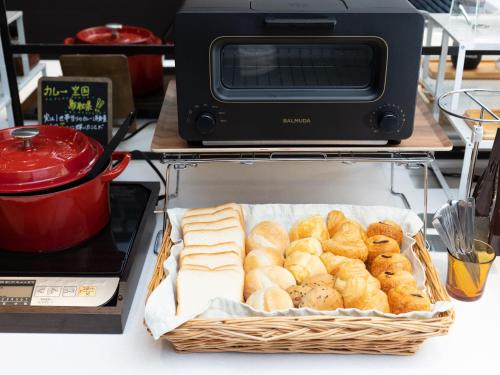 a basket of bread and a toaster oven on a counter at Super Hotel Tottori Ekimae in Tottori