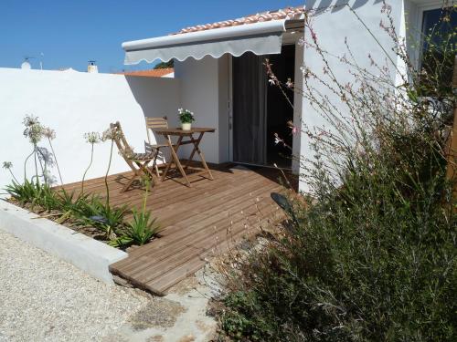 une terrasse en bois avec une table en face d'une maison dans l'établissement Yeu Autrement, à L'Ile d'Yeu