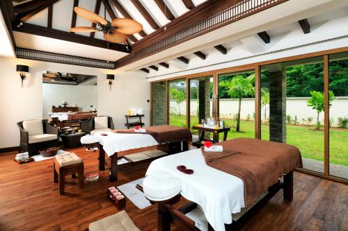 a hotel room with a bed, table, chairs and a window at Savoy Seychelles Resort & Spa in Beau Vallon