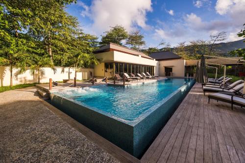 a swimming pool with chairs and a house at Savoy Seychelles Resort & Spa in Beau Vallon