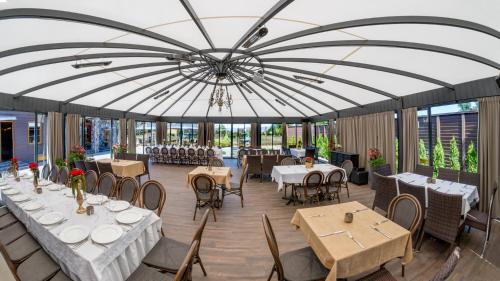 a restaurant with tables and chairs under a large tent at Hotel - Bar Grafaite in Šiauliai