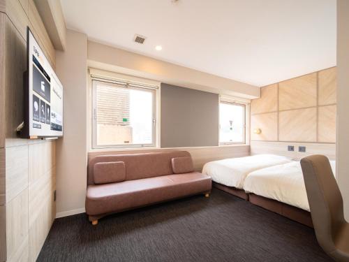 a bedroom with a bed and a couch and a tv at Super Hotel Tottori Ekimae in Tottori
