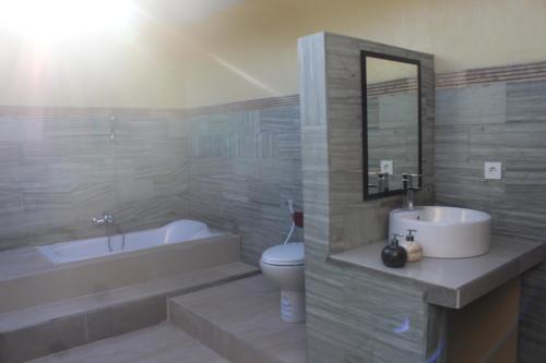 Un baño con lavabo, bañera e inodoro. en Taman Padi Villa, en Amed