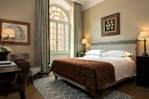 a bedroom with a bed and a desk and a window at Rocco Forte Hotel De La Ville in Rome
