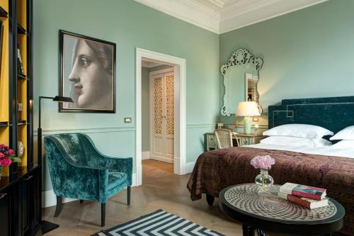 a bedroom with a bed and a chair and a table at Rocco Forte Hotel De La Ville in Rome