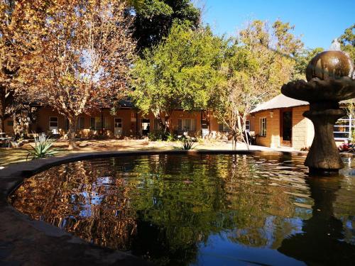 a fountain in the middle of a pond in front of a building at Aruka in Bela-Bela