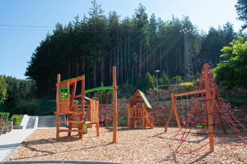 a playground with wooden play equipment in a park at Ruskovets Thermal SPA & Ski Resort in Bansko