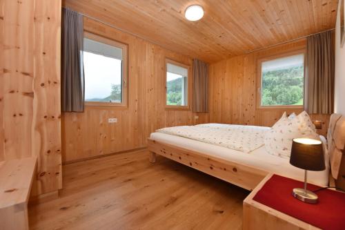 a bedroom in a log cabin with a bed and two windows at Ferienhof Felder in Bezau