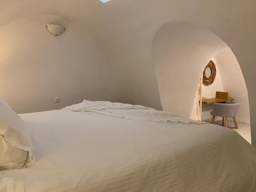 a white bed in a room with an archway at Imer Villas in Imerovigli