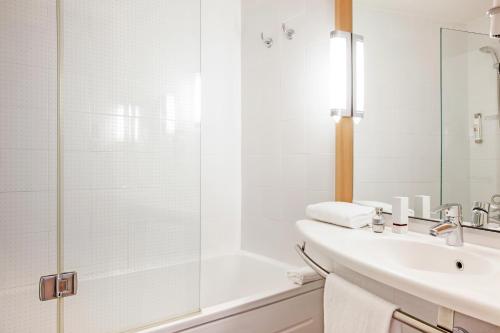 a white bathroom with a sink and a shower at Ibis Barcelona Mollet in Mollet del Vallès