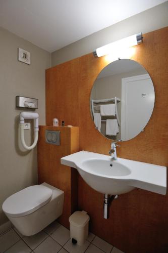 a bathroom with a sink and a toilet and a mirror at Hôtel du Parc Nantes Ouest Orvault in Orvault