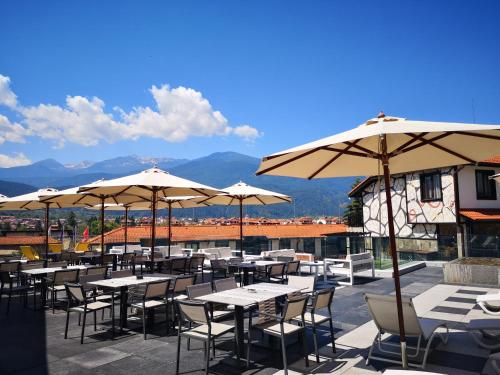 a patio with tables and chairs with umbrellas at Ruskovets Thermal SPA & Ski Resort in Bansko