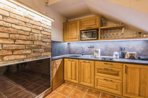 a kitchen with wooden cabinets and a brick wall at Vinoza - ubytování a vinný sklep v Moravském Toskánsku in Hovorany