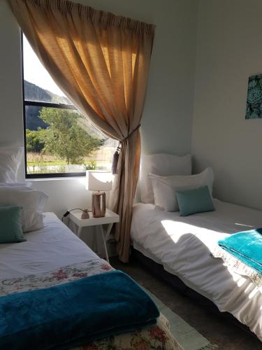 1 dormitorio con 2 camas y ventana en Matjesfontein Estate Keurbooms Chalet, en Plettenberg Bay