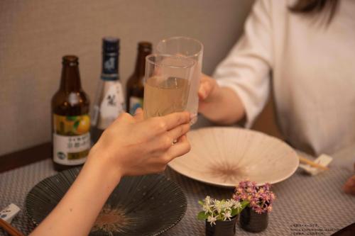 a woman holding a glass of wine on a table at Stay SAKURA Kyoto Fuga in Kyoto
