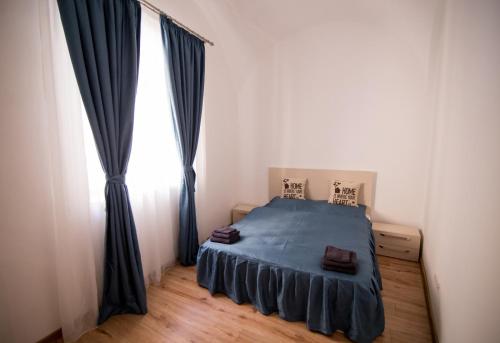 Un dormitorio con una cama azul y una ventana. en Heart of city apartament, en Oradea