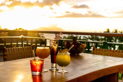 a wooden table with three drinks on a balcony at Savoy Seychelles Resort & Spa in Beau Vallon