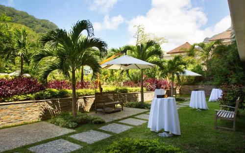 a patio with two tables and an umbrella at Savoy Seychelles Resort & Spa in Beau Vallon