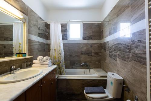 a bathroom with a sink and a toilet and a tub at Marble Villa in Fotinós