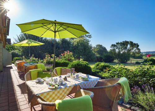 a dining table with a yellow umbrella on a patio at Hotel An der Brunnader - Die Therme befindet sich 4 Geh-Minuten entfernt in Bad Birnbach