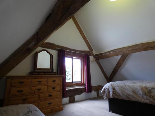 a bedroom with a window and a dresser and a mirror at Yew Tree Barn in Prees