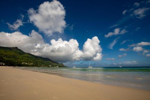 a sandy beach with a boat in the water at Savoy Seychelles Resort & Spa in Beau Vallon