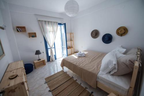 a white bedroom with a bed and a wooden table at Aquarella-stylish veranda apartment in centre of Poros town in Poros