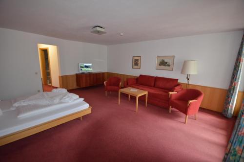 a living room with a red couch and chairs at Posthotel Rössle in Gaschurn