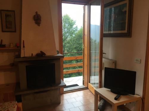 a living room with a television and a sliding glass door at Casa Neve in Abetone