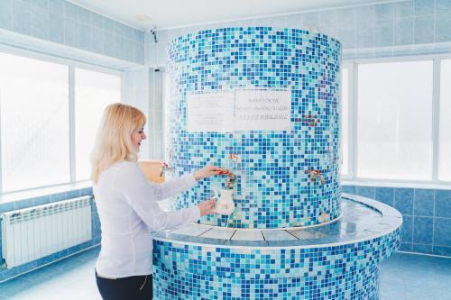 uma mulher em pé em frente a um chuveiro de azulejos azuis em Kvasova Voda em Polyana