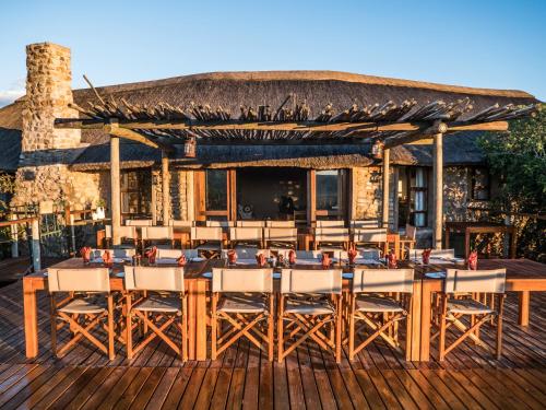 a restaurant with wooden tables and chairs on a deck at Woodbury Tented Camp – Amakhala Game Reserve in Amakhala Game Reserve