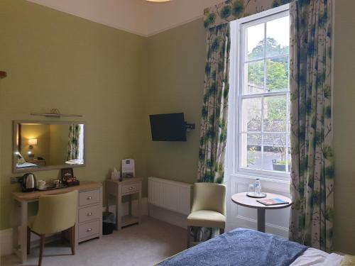 a bedroom with a bed and a desk and a window at The Osborne Hotel in Torquay