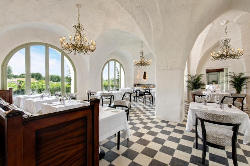 a restaurant with white tables and chairs and chandeliers at Rocco Forte Masseria Torre Maizza in Savelletri di Fasano