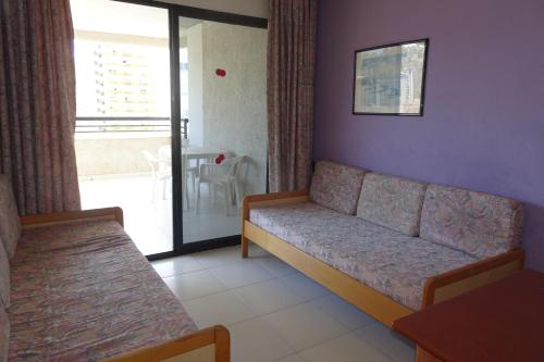a living room with a couch and a balcony at Luxmar Apartaments in Benidorm