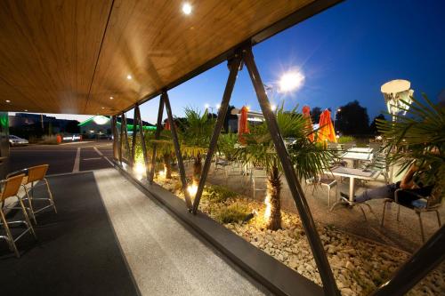 a view of a patio at night with palm trees at Kyriad Clermont Ferrand Nord - Riom in Riom