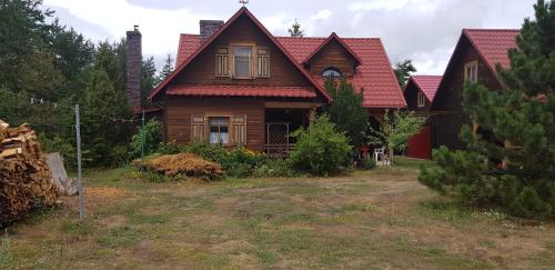 a wooden house with a red roof at Agroturystyka Ruta nad zalewem Siemianówka in Łuka