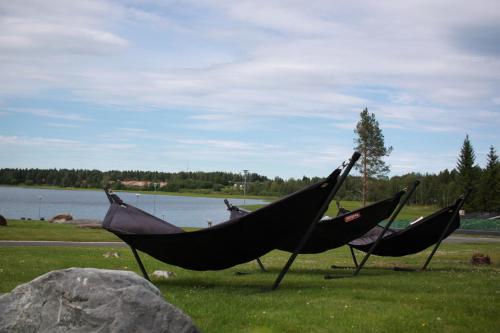 three hammocks sitting in a field next to a lake at Hotel Aateli Lakeside in Vuokatti