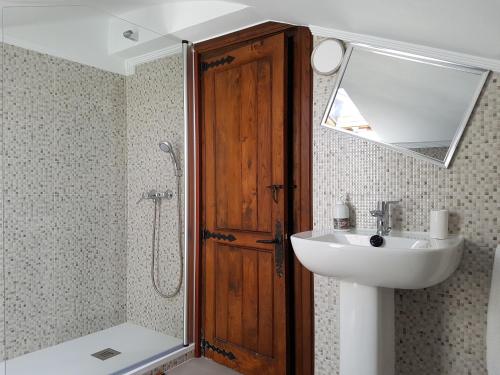 a bathroom with a sink and a shower with a mirror at Pension Castio in Santillana del Mar