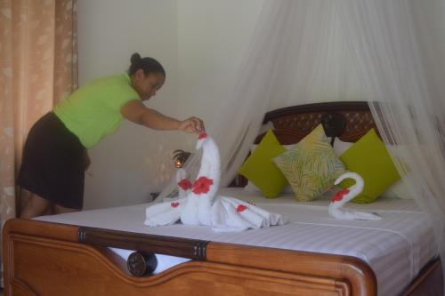 a woman is standing on a bed with two dolls at Chalet Bamboo Vert in La Digue