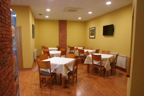 uma sala de jantar com mesas brancas e cadeiras de madeira em Albergue La Encina em Hospital de Órbigo
