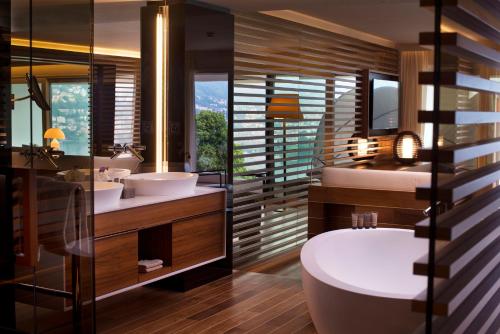 een badkamer met 2 wastafels, een bad en een toilet bij The View Lugano in Lugano