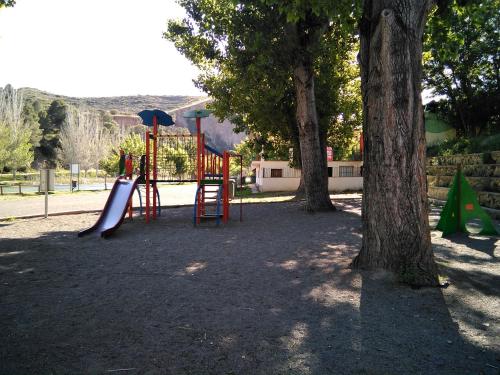 einen Spielplatz mit Rutsche und zwei Bäumen in der Unterkunft Adosado, cerca de Valencia en zona de montaña y playa fluvial in Valencia