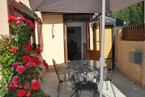 a patio with a table and chairs under an umbrella at GÎTE Le Moulineau in Deville