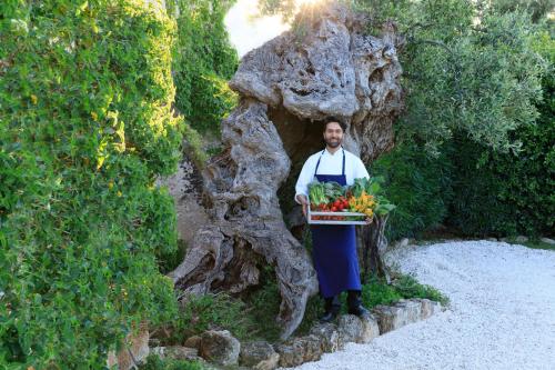 a man holding a basket of fruits and vegetables at Rocco Forte Masseria Torre Maizza in Savelletri di Fasano