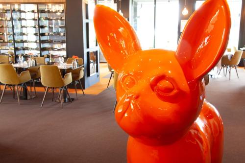 an orange statue of a rabbit in a restaurant at Kyriad Clermont Ferrand Nord - Riom in Riom