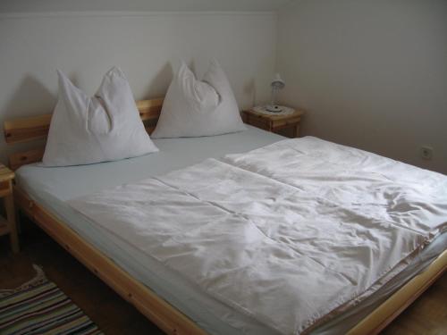 Una cama con sábanas blancas y almohadas. en Ferienwohnung Schimun en Eberndorf
