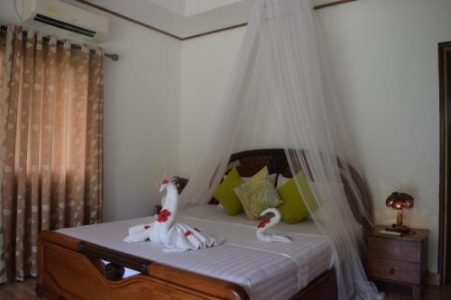 a bedroom with a bed with two swans on it at Chalet Bamboo Vert in La Digue
