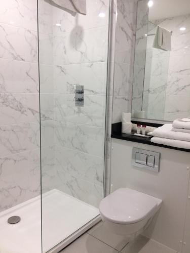 a white bathroom with a shower and a toilet at Falls Hotel & Spa in Ennistymon